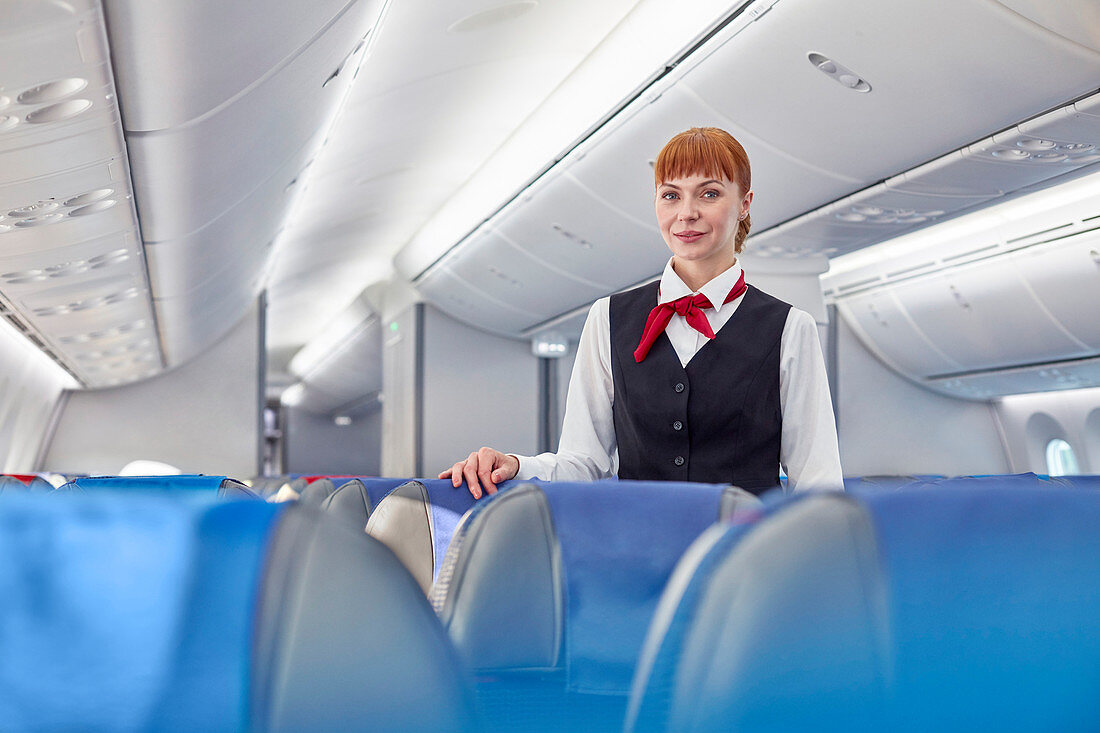 Portrait confident flight attendant on airplane