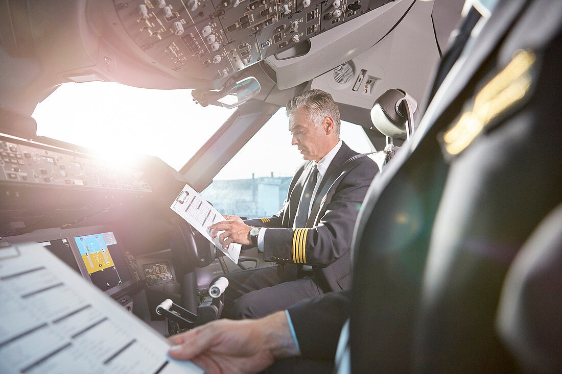 Male pilots preparing in airplane cockpit