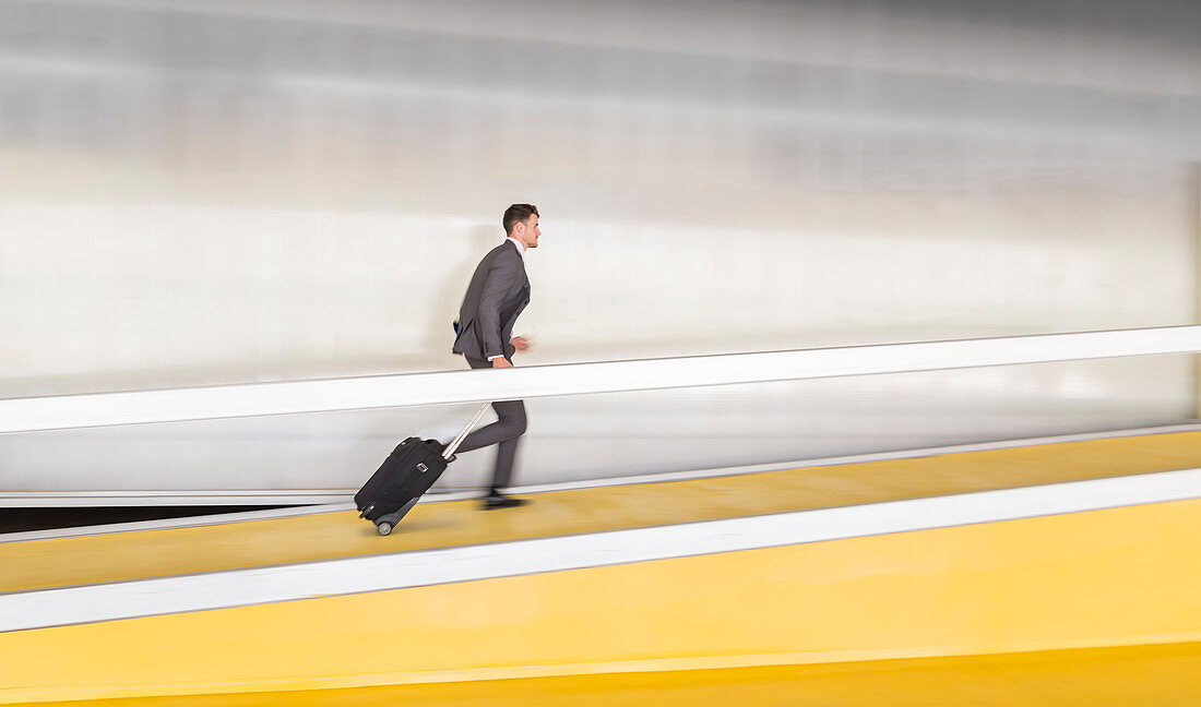 Businessman pulling suitcase up airport ramp