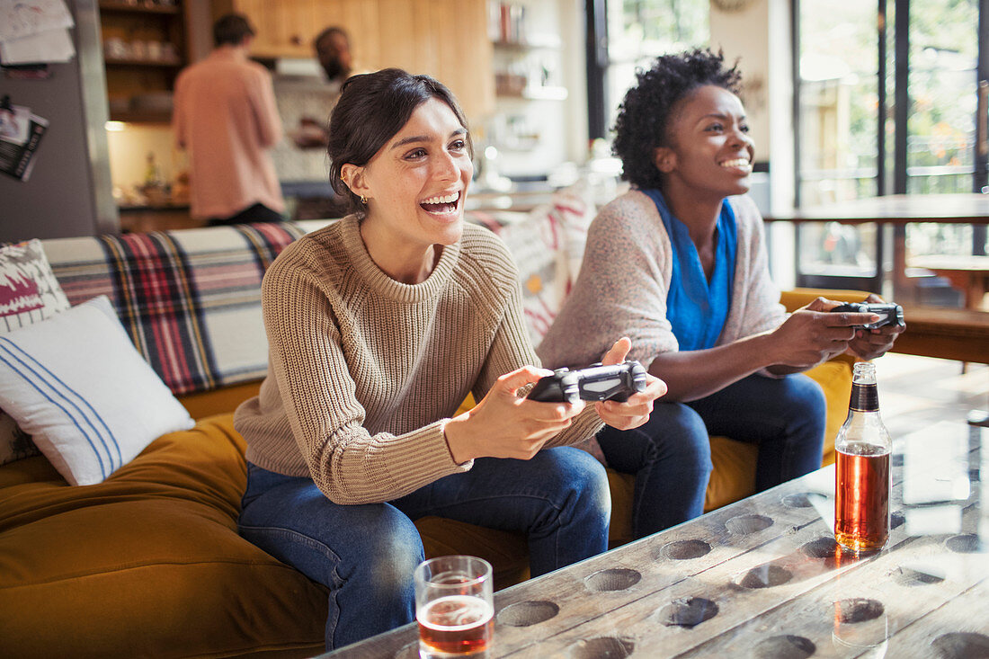 Laughing women friends playing video game