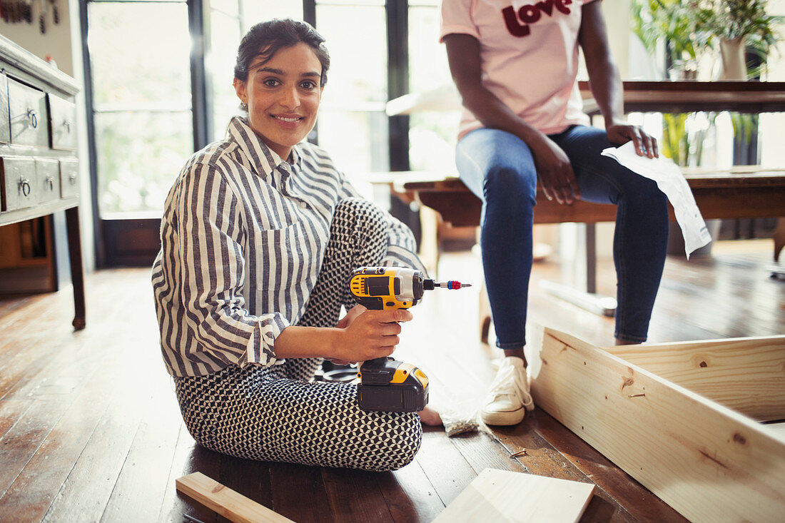 Woman with power drill assembling furniture