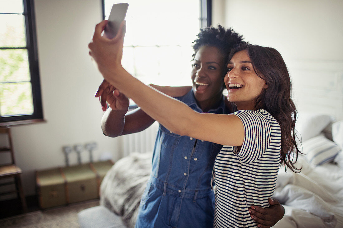 Smiling lesbian couple hugging, taking selfie