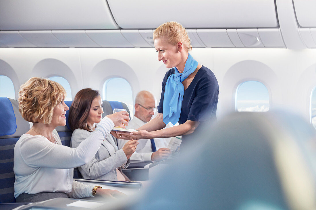 Flight attendant serving drink to woman