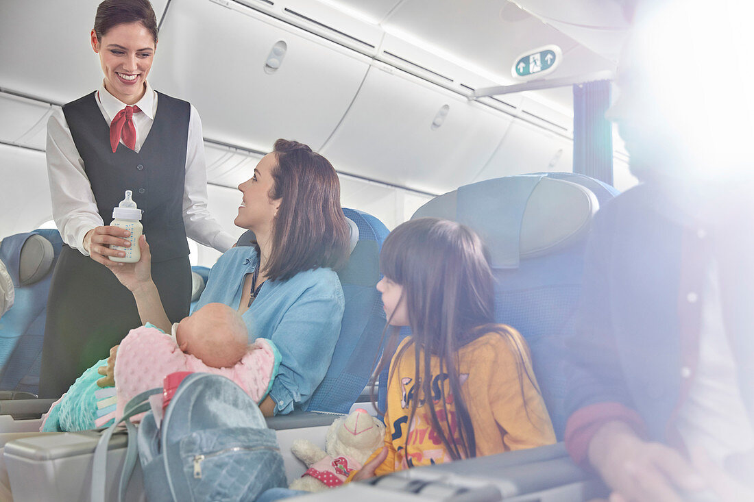 Smiling flight attendant bringing baby bottle