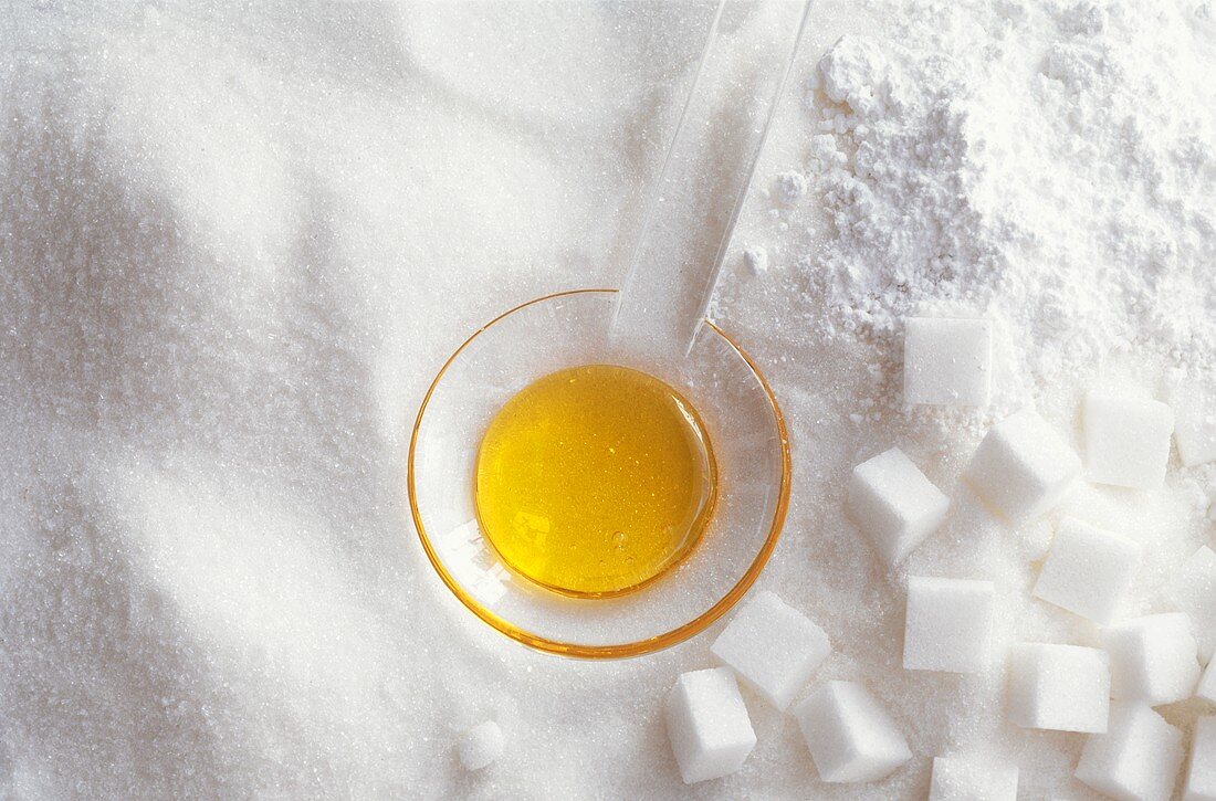 Glass spoon with honey on crystallised, icing & cubed sugar