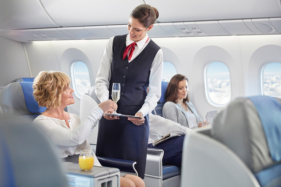 Flight attendant serving champagne to woman