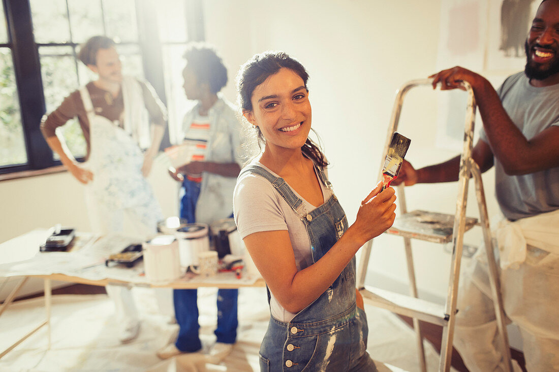 Portrait woman painting living room with friends