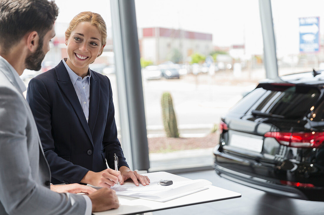 Car saleswoman and customer signing contract