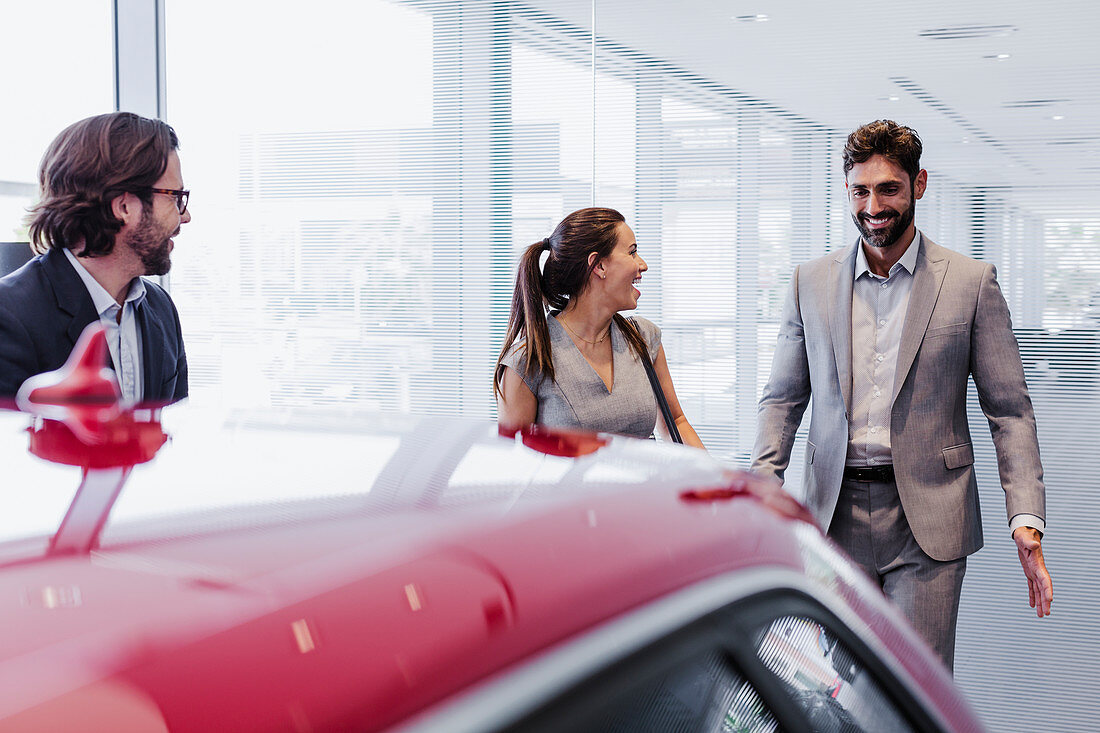 Car salesman and couple customers looking at car