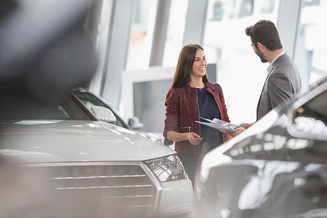 Car saleswoman showing brochure to customer