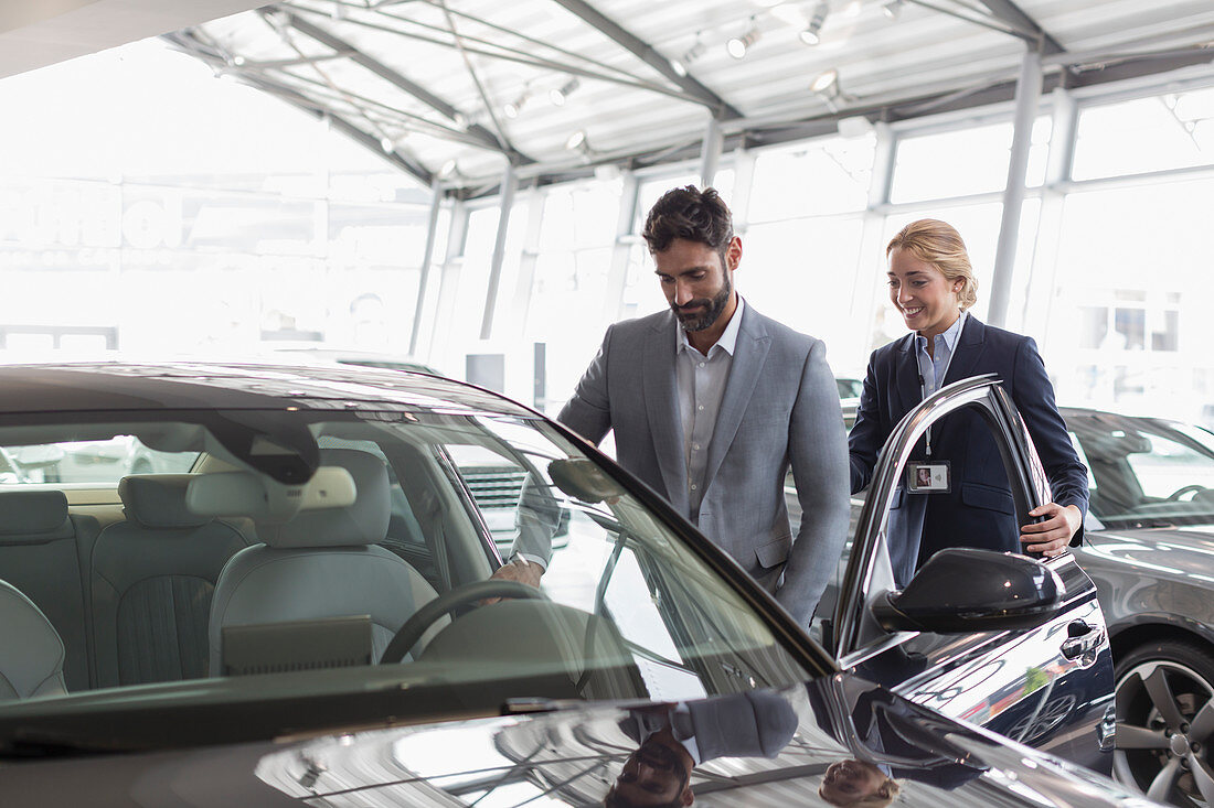 Car saleswoman showing car to customer in showroom