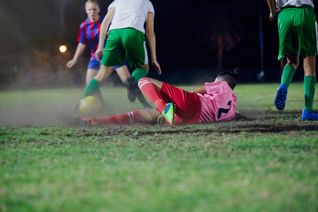 Soccer player falling, kicking the ball