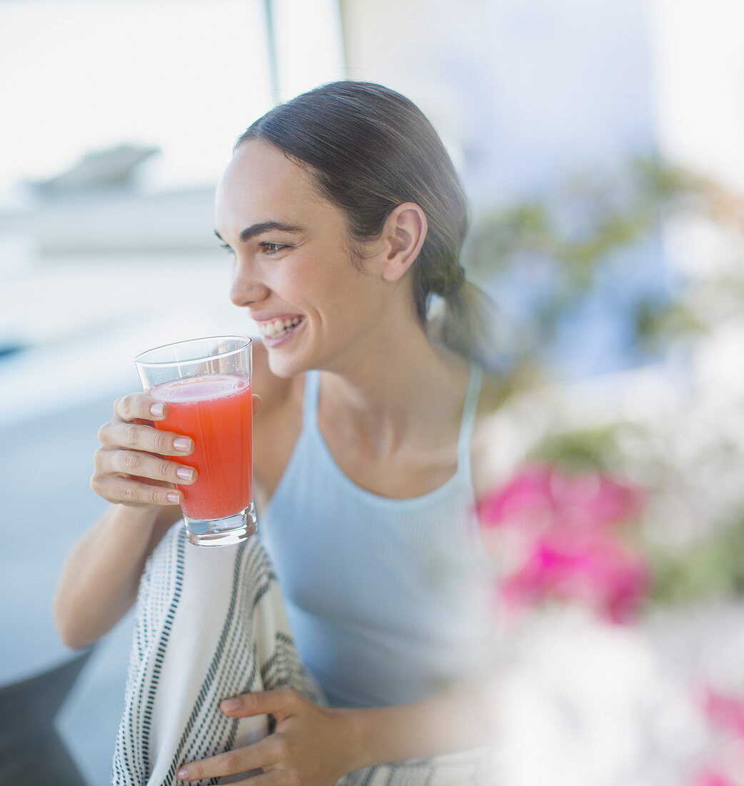 Smiling brunette woman in pyjamas drinking juice