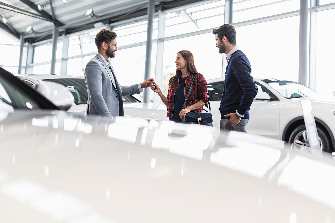 Car salesman giving car keys to customers