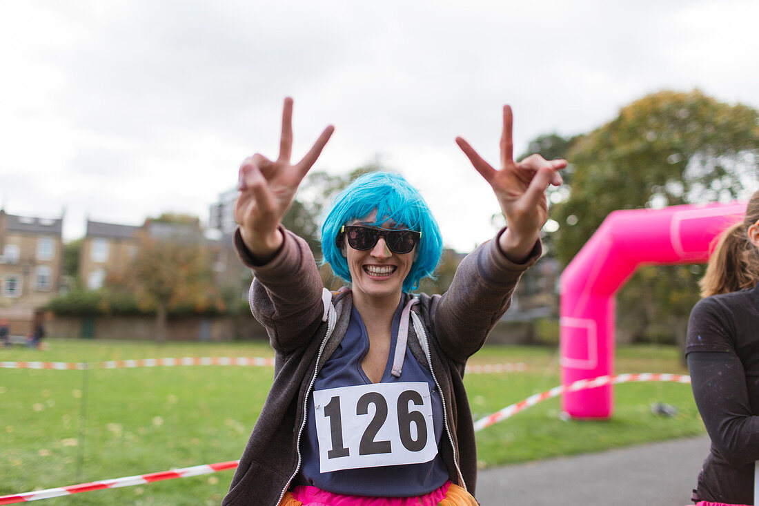 Portrait runner in wig gesturing peace sign