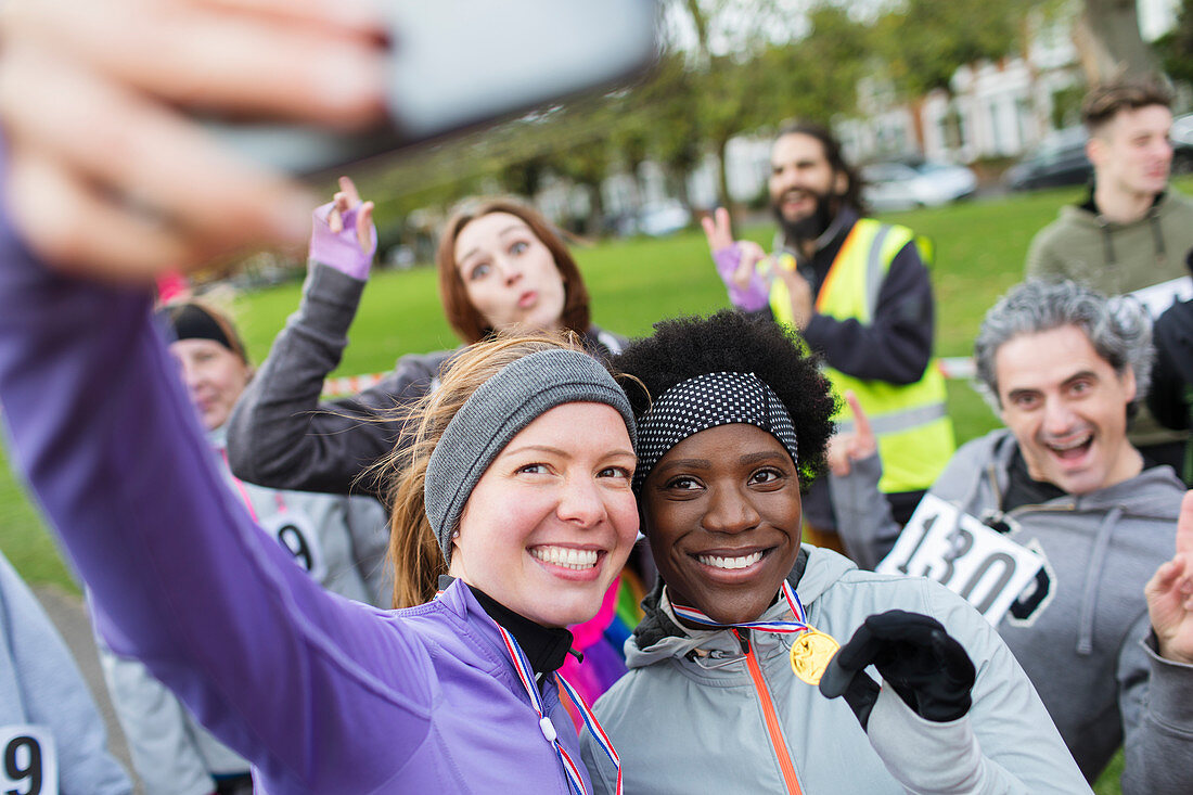 Smiling female runners with medal taking selfie