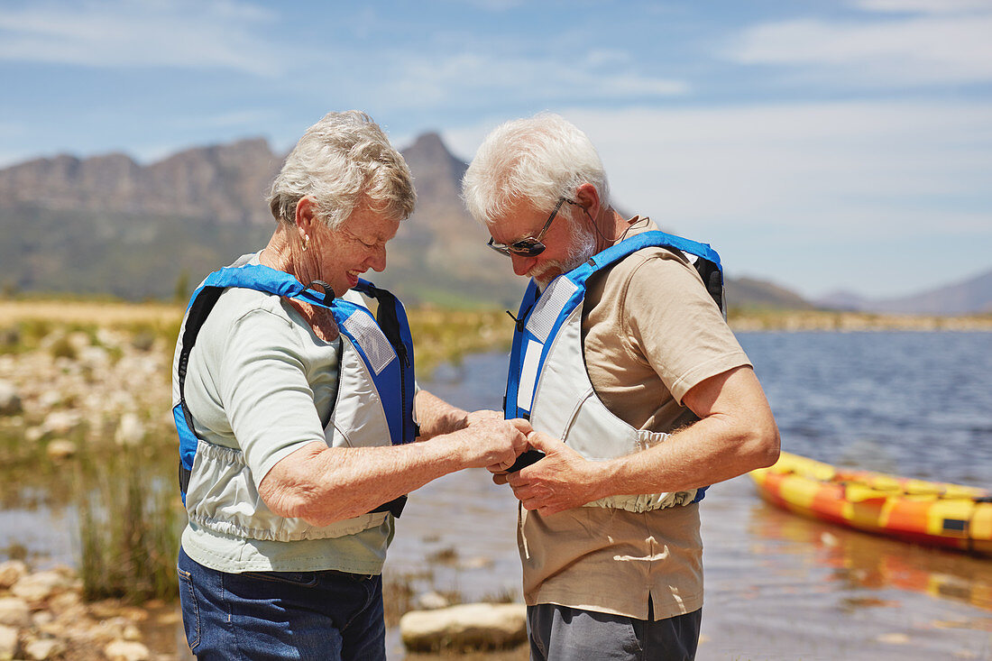 Active senior couple putting on life jackets