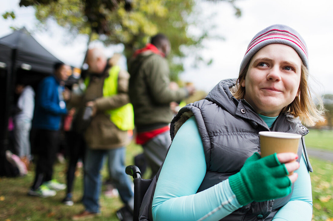 Woman in wheelchair drinking coffee in park