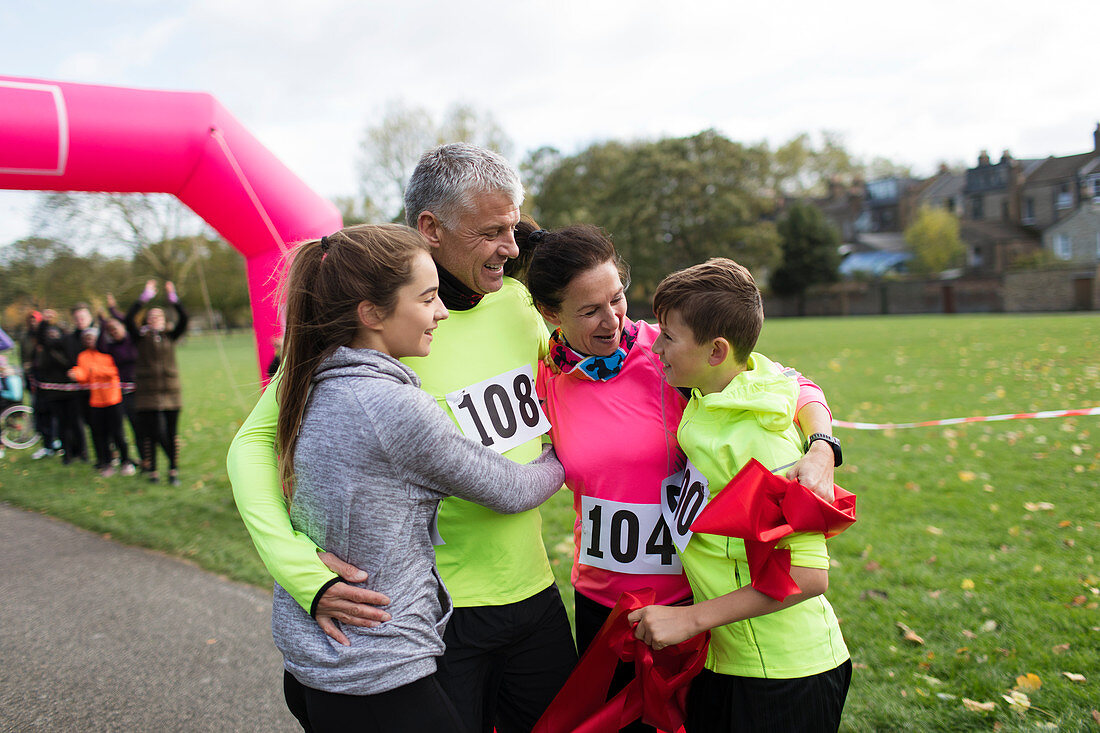 Happy family hugging at charity run in park