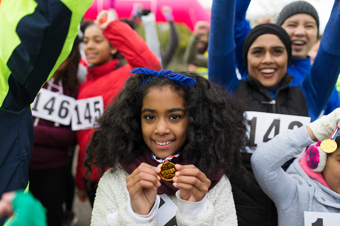Portrait smiling girl runner showing medal