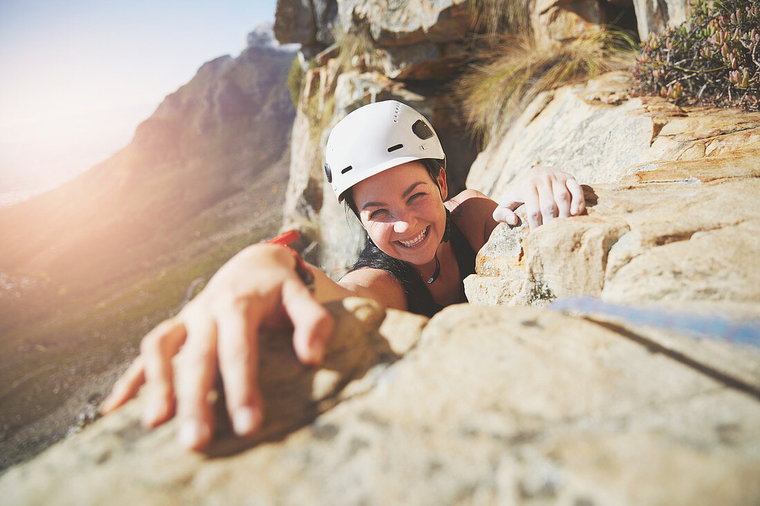Portrait smiling, rock climber reaching for rock