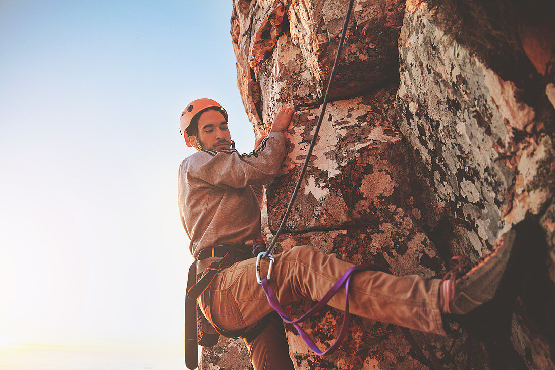 Focused male rock climber hanging from rock