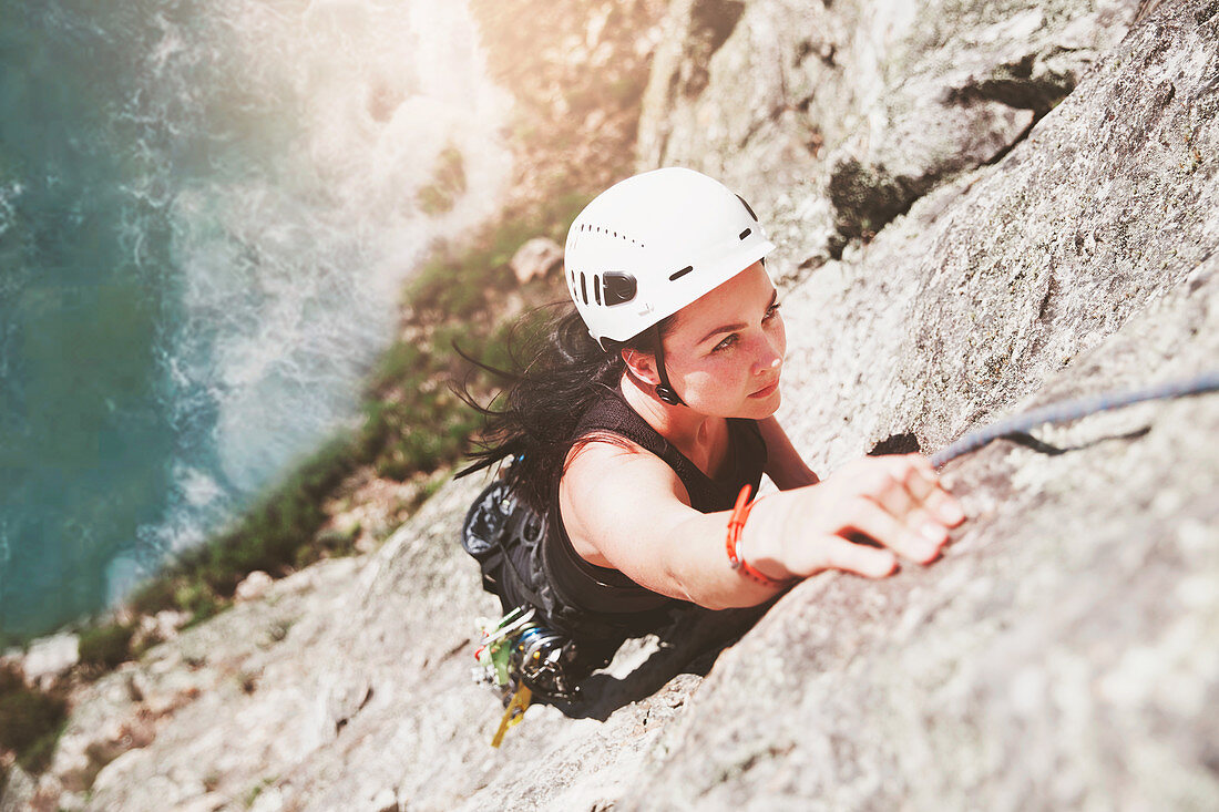 Focused, determined rock climber scaling rock