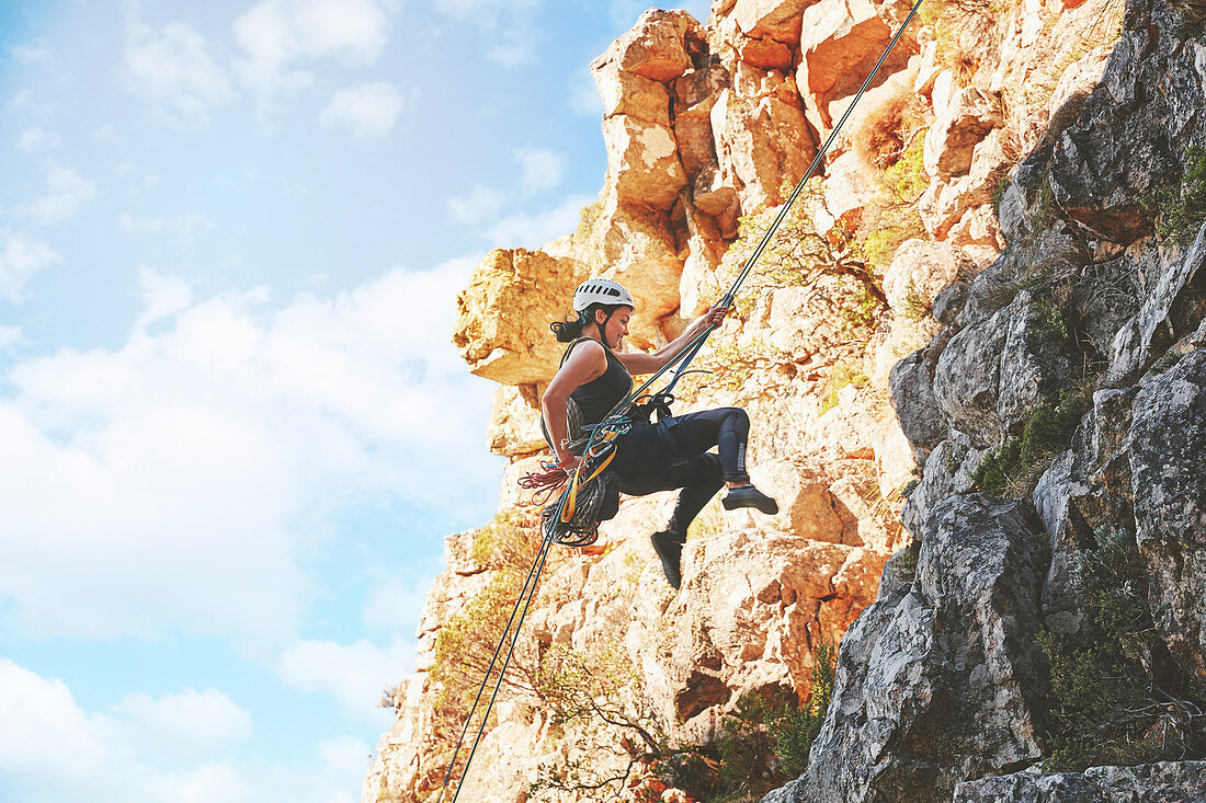 Female rock climber descending rocks