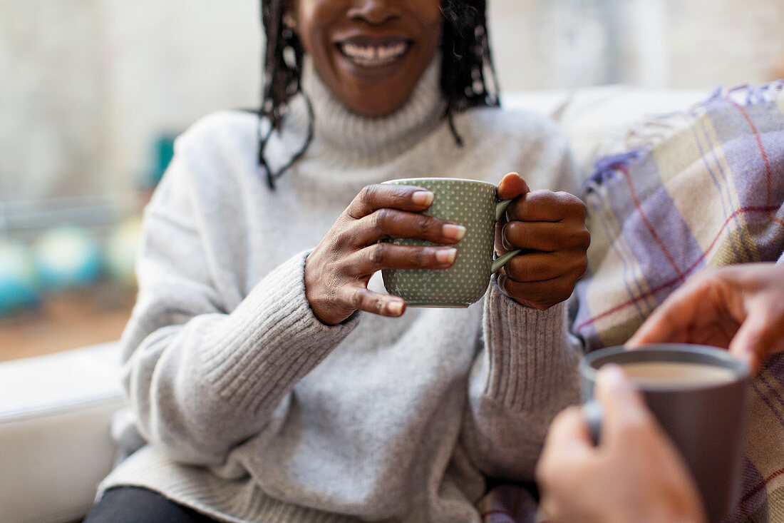 Women talking and drinking tea on sofa