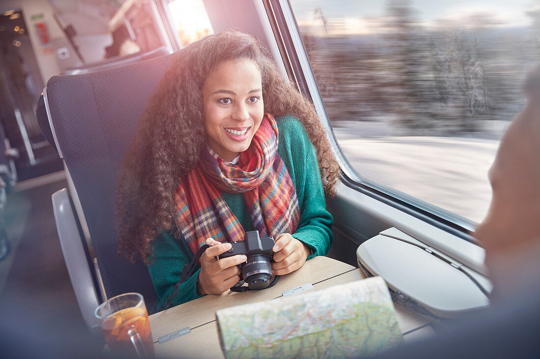 Young woman with camera and map riding train