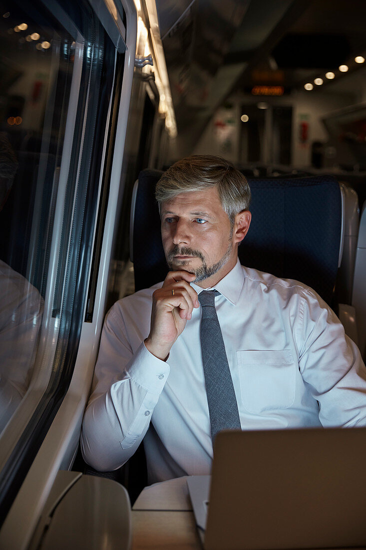 Businessman working at laptop on train