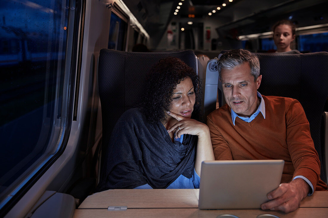 Couple using digital tablet on dark train at night
