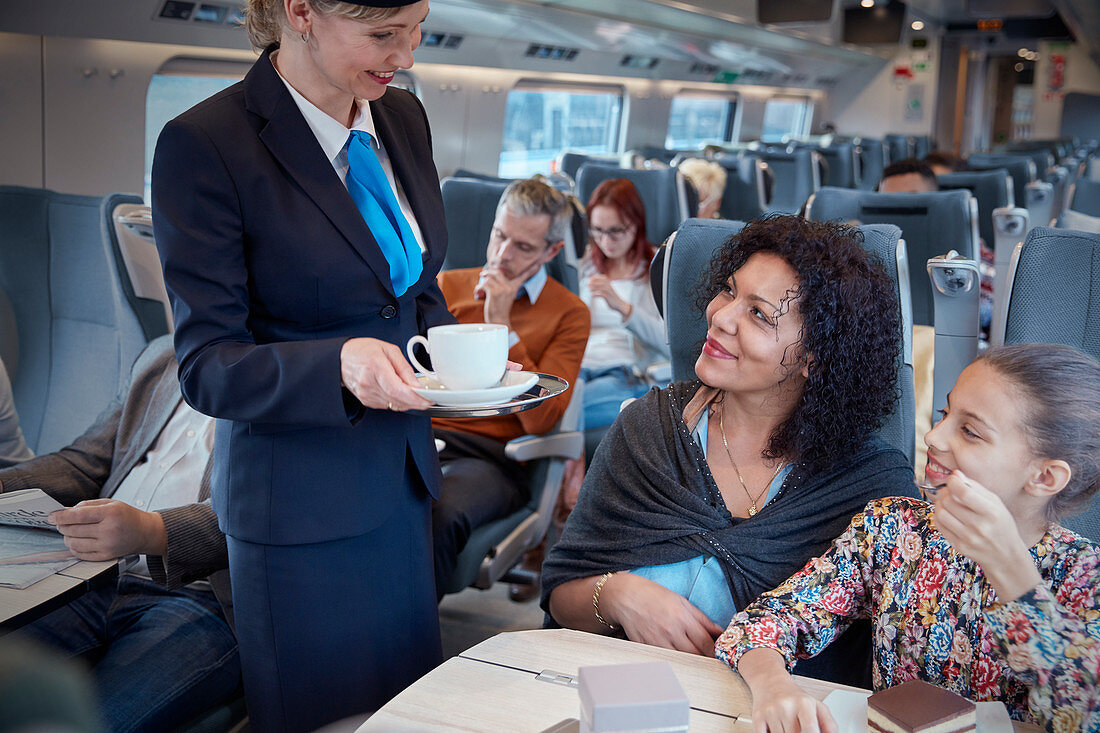 Attendant serving coffee to mother on train