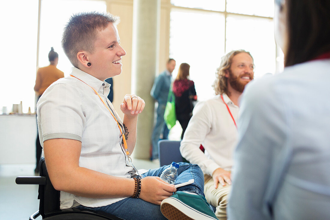 Woman in wheelchair talking to colleagues at conference