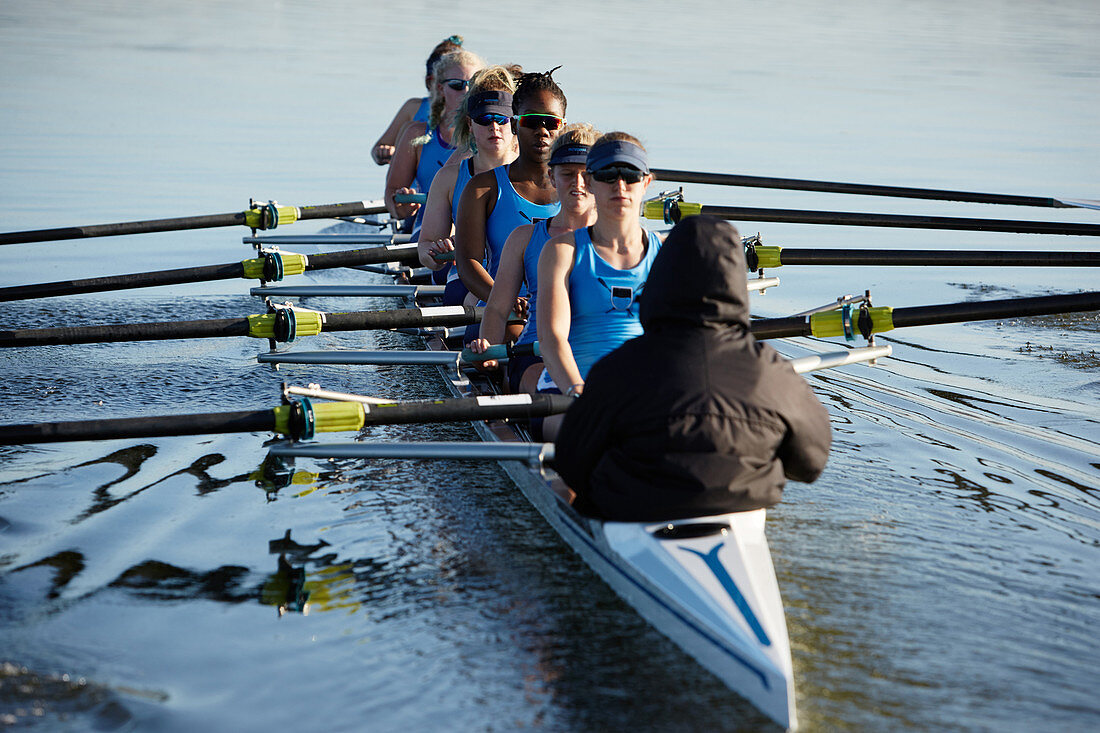 Female rowers rowing scull on lake