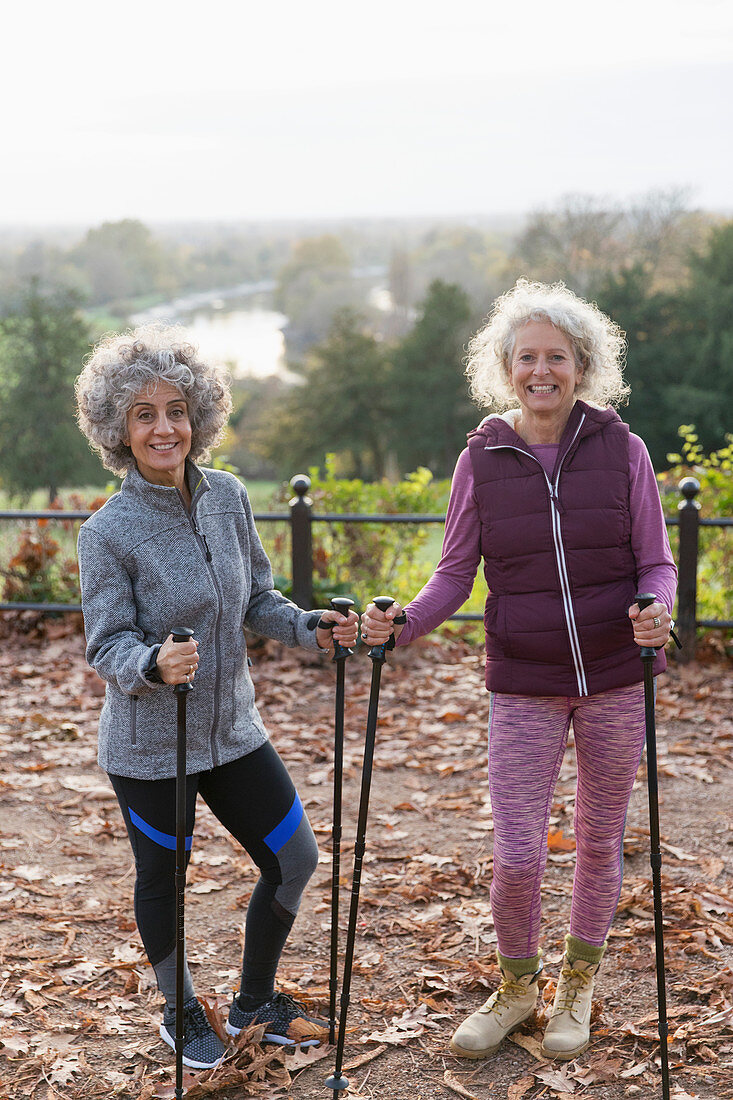 Portrait active senior women friends hiking with poles