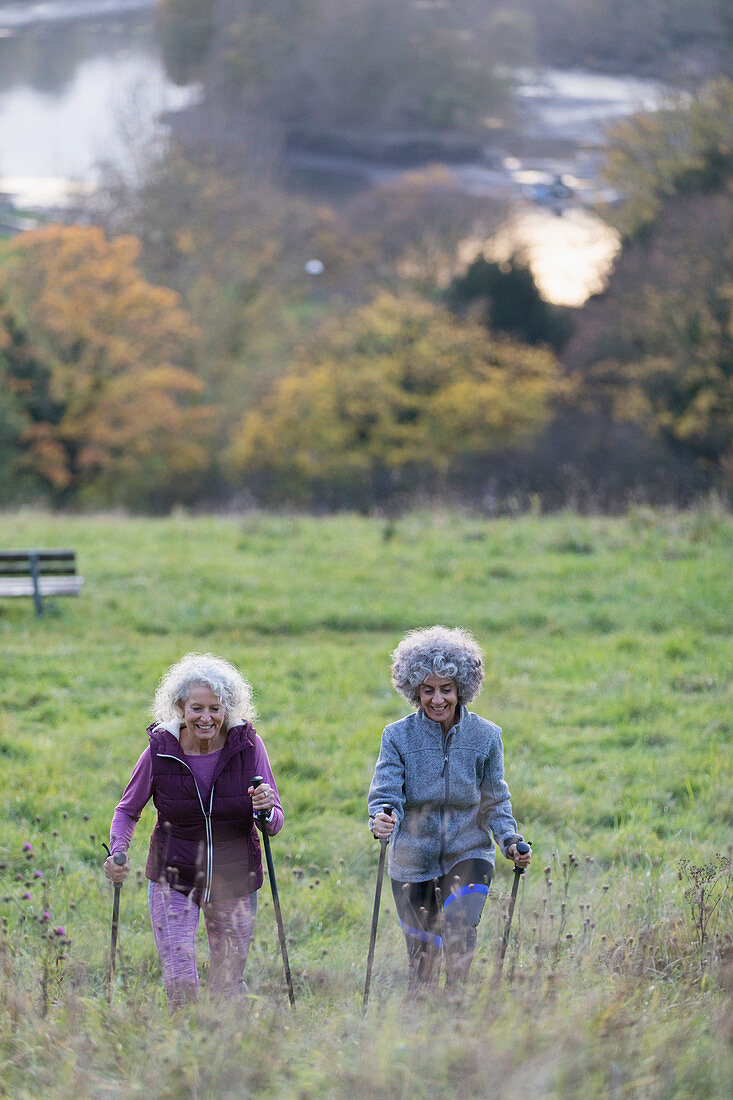 Active senior women friends hiking with poles