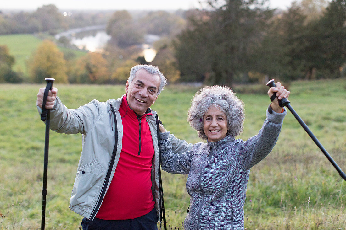 Portrait enthusiastic, senior couple hiking with poles