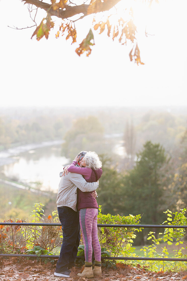 Affectionate senior couple hugging in sunny autumn park