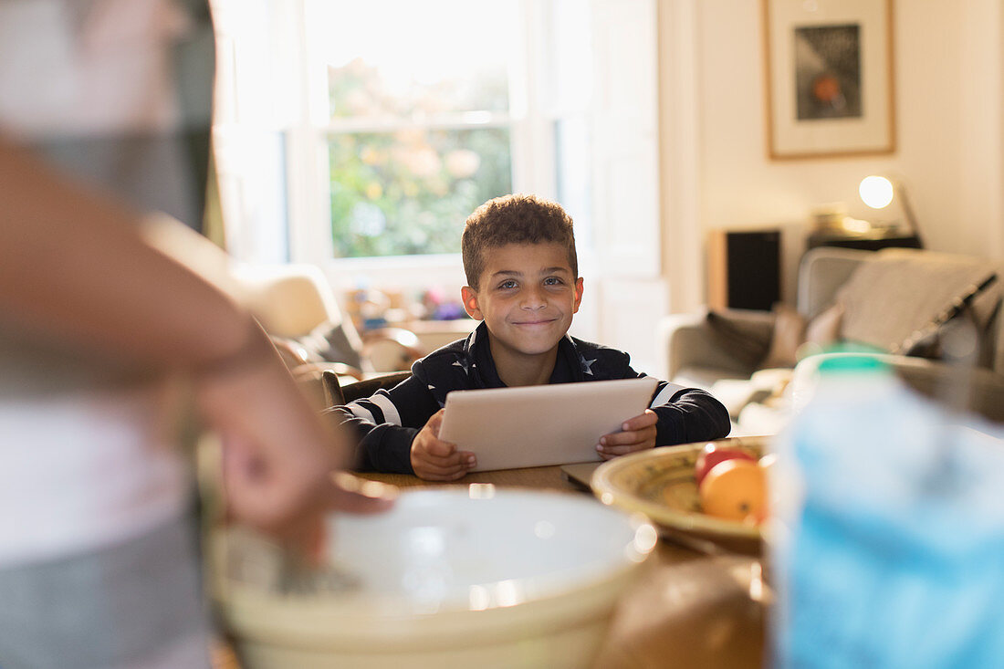 Portrait smiling boy using digital tablet in kitchen