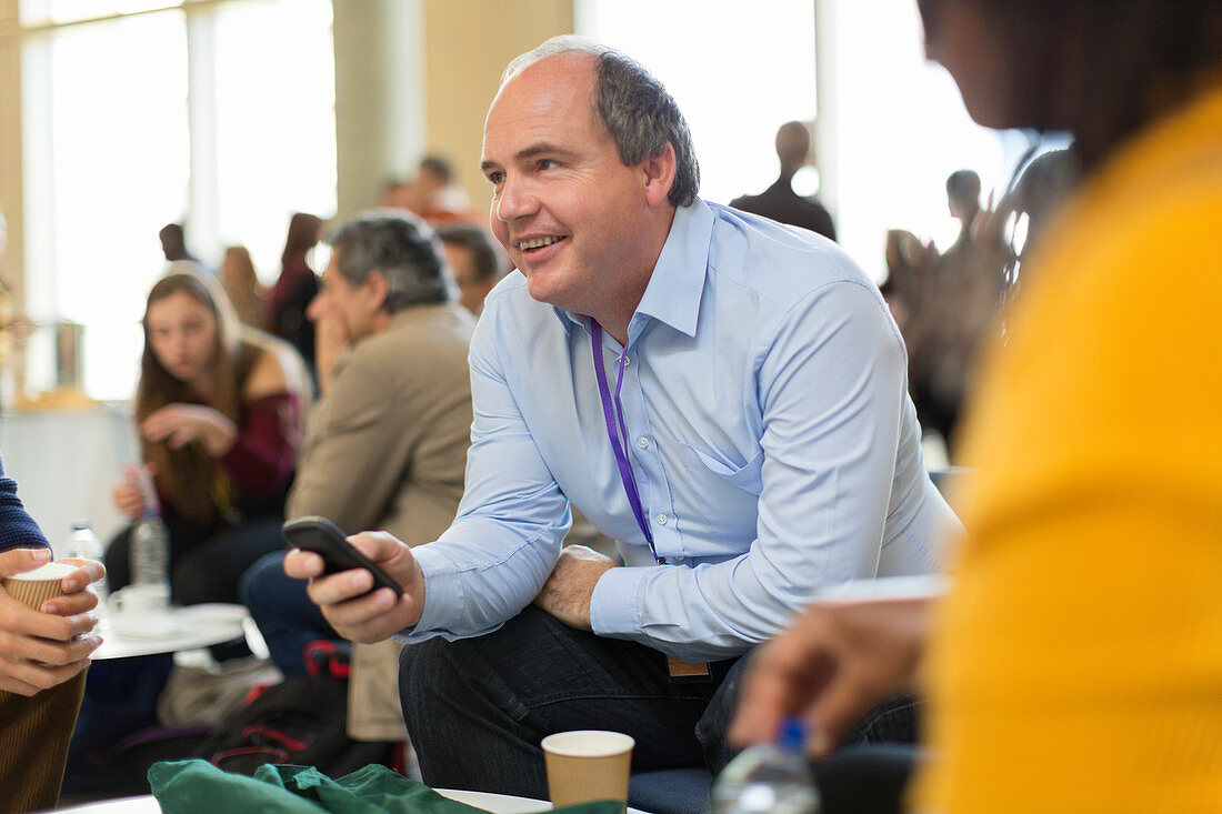 Smiling businessman using smart phone at conference