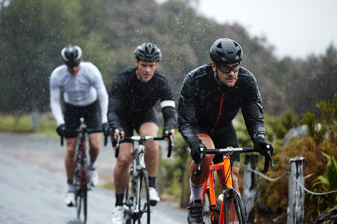 Dedicated male cyclists cycling on rainy road