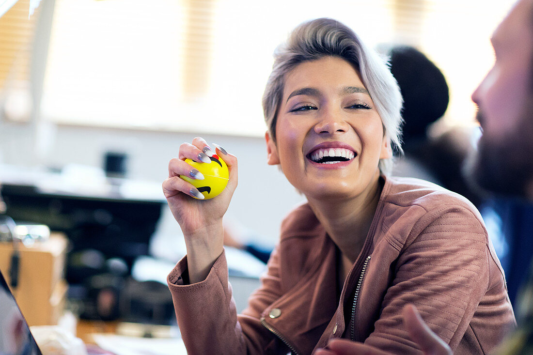 Laughing Businesswoman squeezing stress ball in office