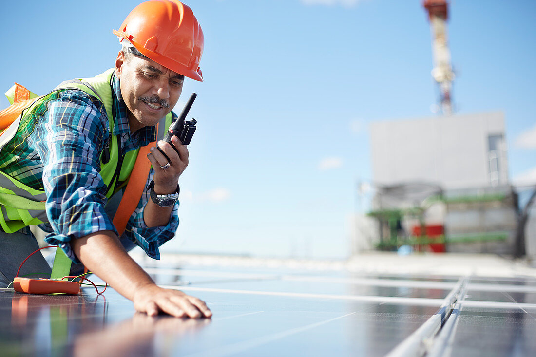 Engineer with walkie-talkie inspecting solar panel