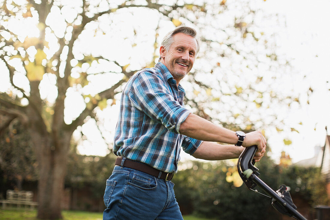 Portrait smiling senior man mowing lawn