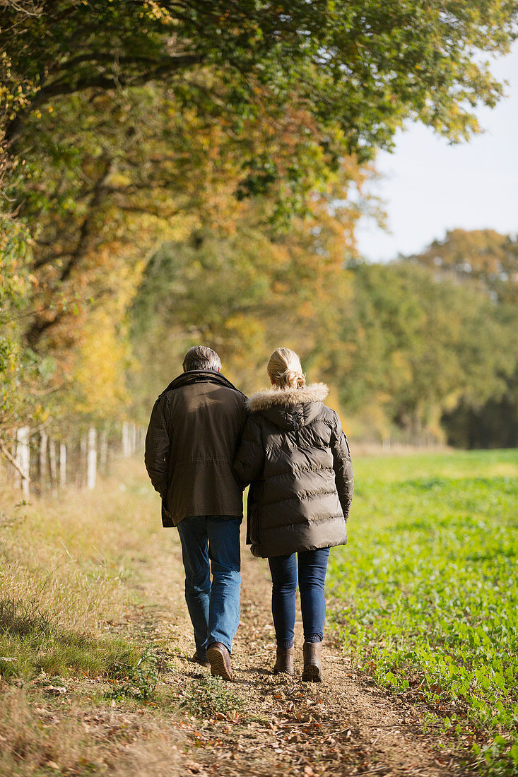 Mature couple walking in sunny, rural autumn field