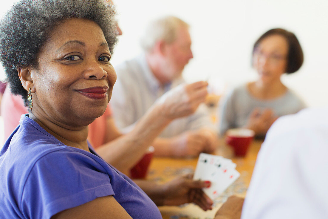 Portrait senior woman playing cards with friends