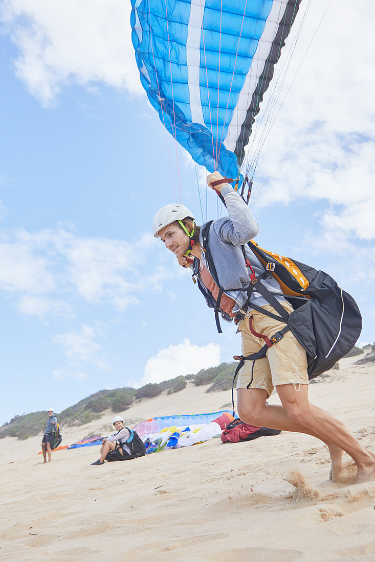 Male paraglider running on beach