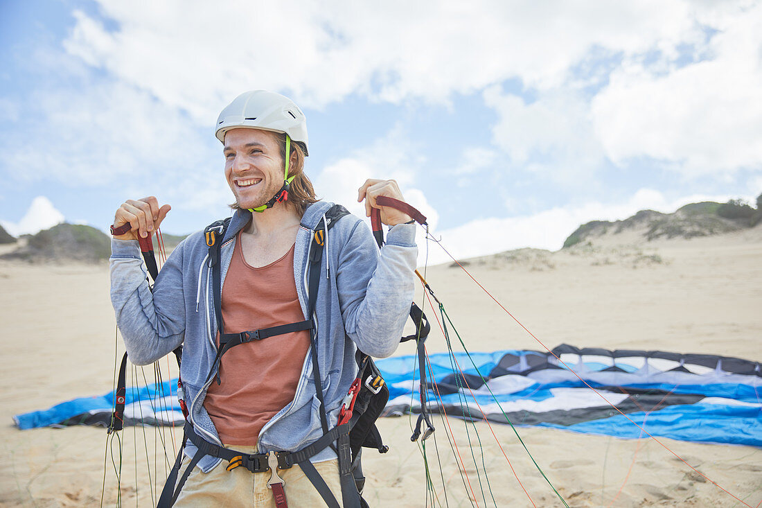 Smiling, paraglider with parachute on beach