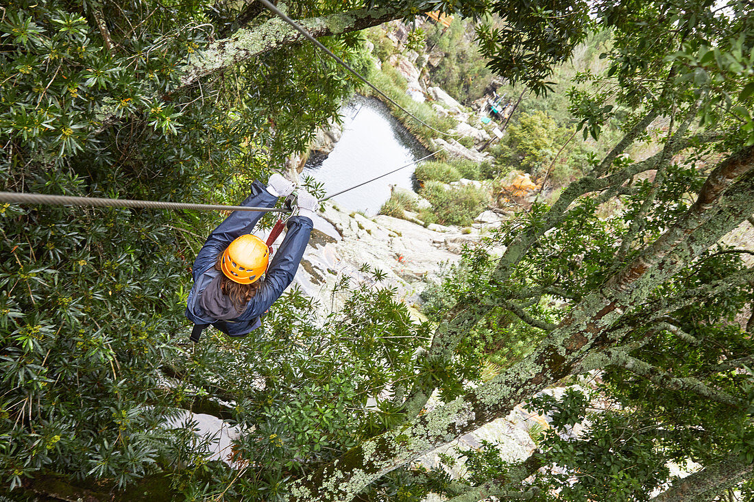 Woman zip lining among trees in woods